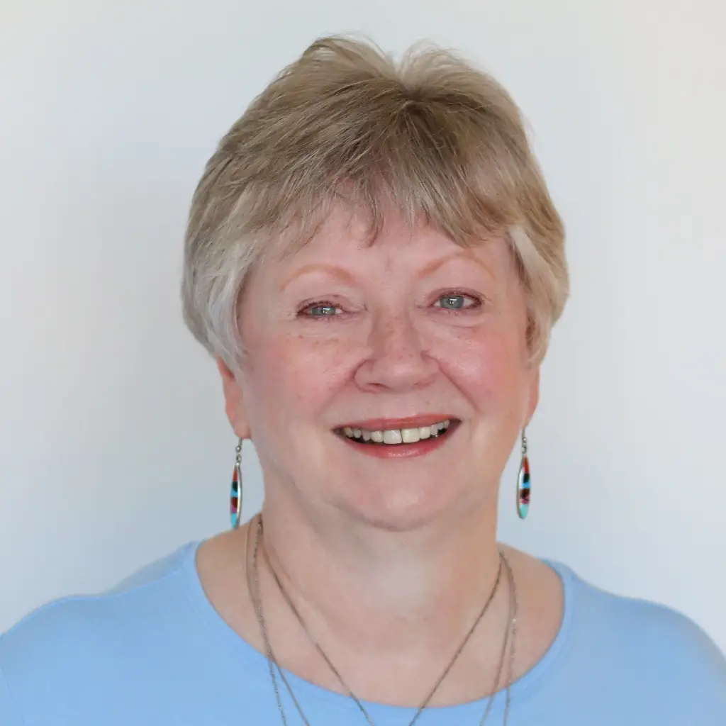 Headshot of the HR manager, smiling in a light blue top with drop earrings.